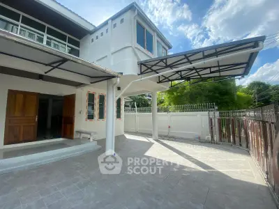 Spacious modern house exterior with covered carport and tiled driveway under a clear blue sky.