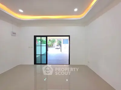 Spacious modern living room with sleek tile flooring and large sliding glass doors opening to a bright outdoor area.