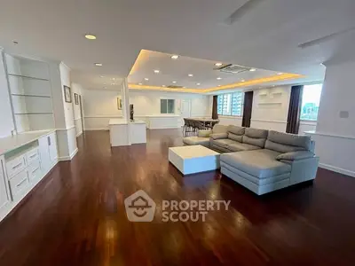 Spacious open-plan living room with elegant hardwood floors and modern furniture in a luxury apartment.