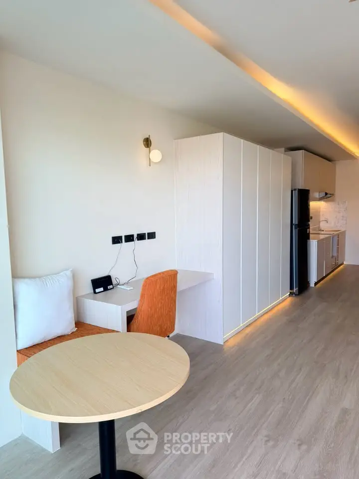 Modern open-plan living area with sleek kitchen and cozy dining space, featuring contemporary lighting and wood flooring.