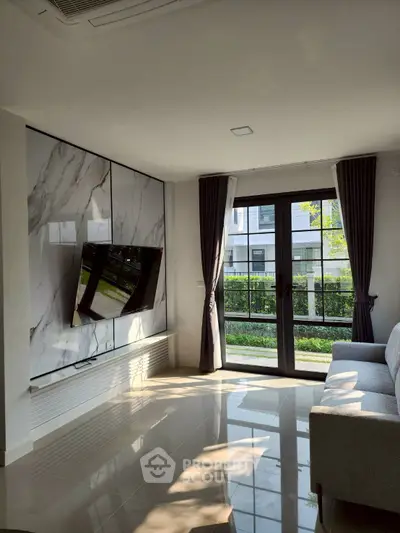 Modern living room with large window, marble accent wall, and sleek TV setup.