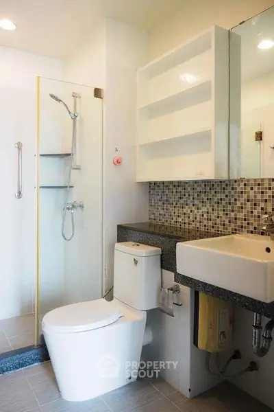 Modern bathroom with sleek fixtures and mosaic tile accents, featuring a spacious shower area and contemporary design.