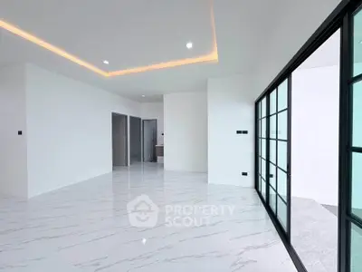 Spacious modern living room with sleek marble flooring and large glass doors opening to a balcony.