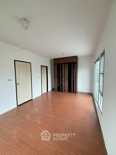 Spacious empty room with wooden flooring and built-in wardrobe