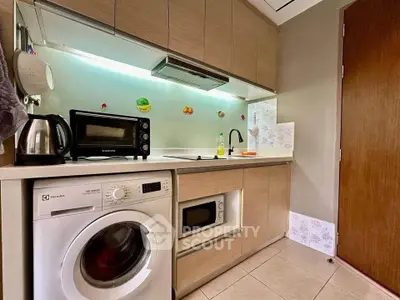 Modern kitchen with washing machine and microwave in compact layout