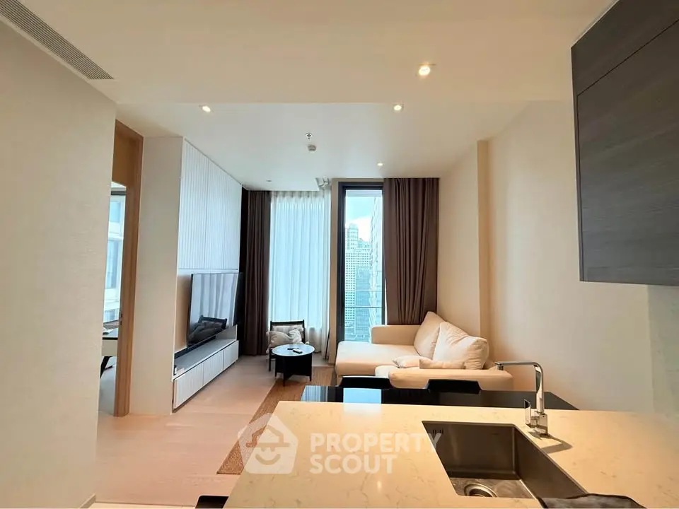 Modern living room with open kitchen and city view, featuring sleek design and cozy ambiance.