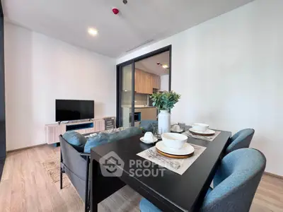 Modern living room with dining area and TV, featuring sleek furniture and open kitchen view.