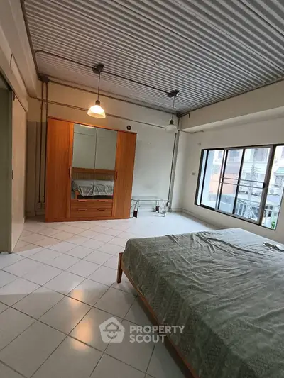 Spacious bedroom with large window and modern furniture