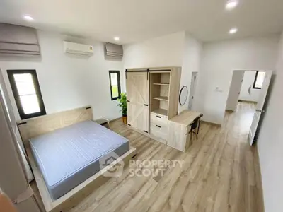 Spacious modern bedroom with wooden flooring and stylish furniture