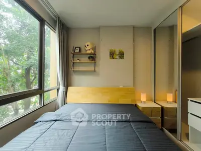 Cozy bedroom with large window and mirrored closet, featuring modern decor and natural light.