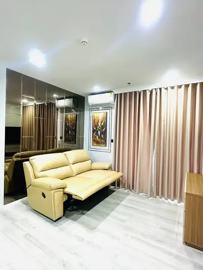 Modern living room with beige leather sofa and mirrored wall, featuring elegant decor and soft lighting.