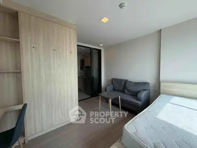 Modern studio apartment with cozy living area and sleek wooden furniture.