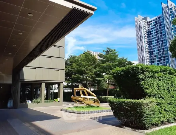 Modern building entrance with lush greenery and cityscape view
