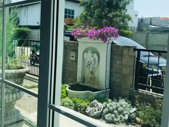 Charming garden view with elegant stone fountain and vibrant flowers, perfect for serene outdoor living.
