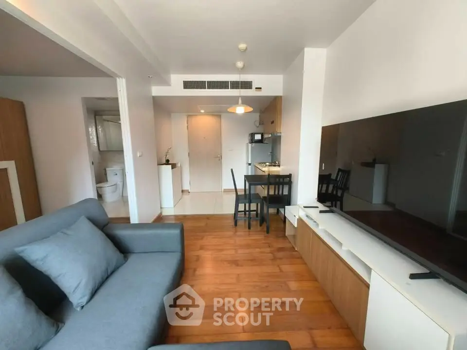 Modern living room with sleek furniture and open layout, featuring a cozy sofa and large TV.