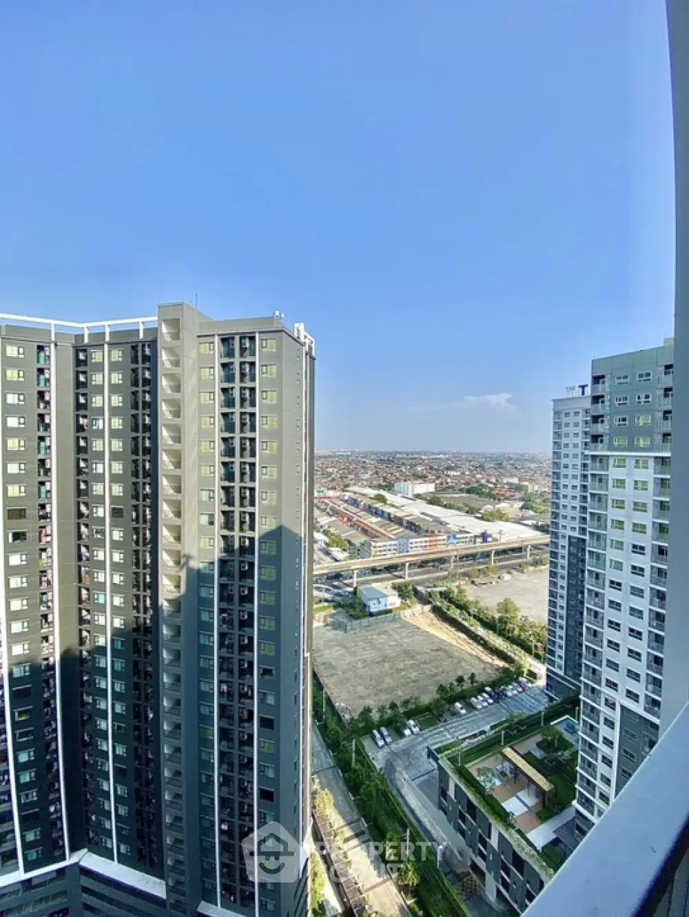 Stunning high-rise apartment view with cityscape and clear blue sky, perfect for urban living.