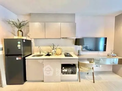 Modern kitchen with sleek cabinets, black fridge, and stylish decor in a compact apartment.