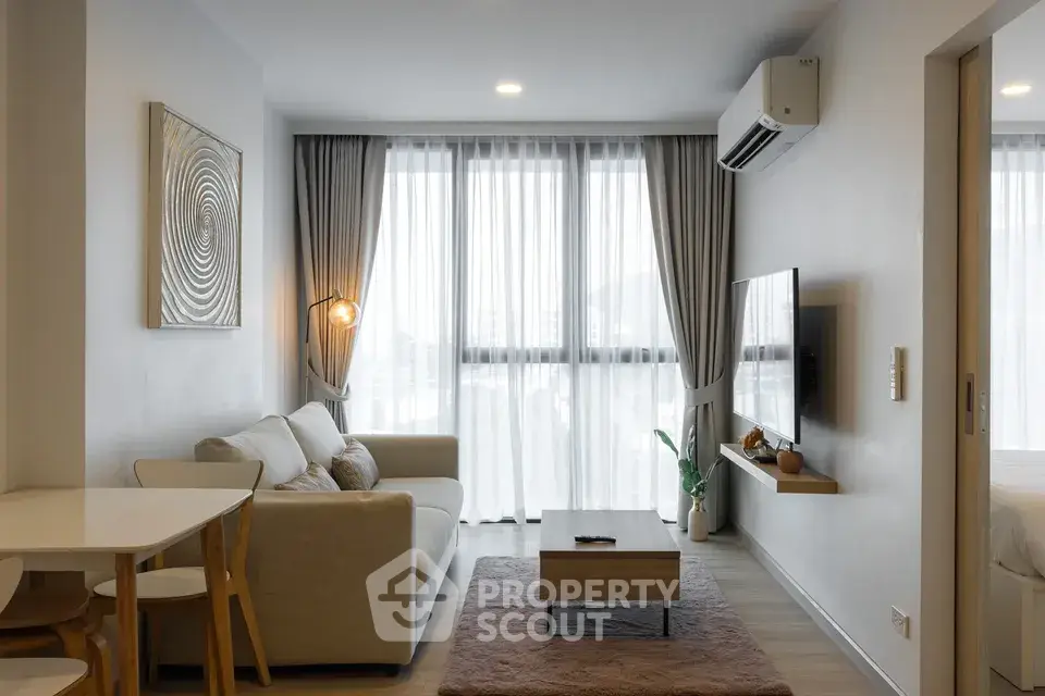 Modern living room with cozy sofa, stylish decor, and natural light from large windows.