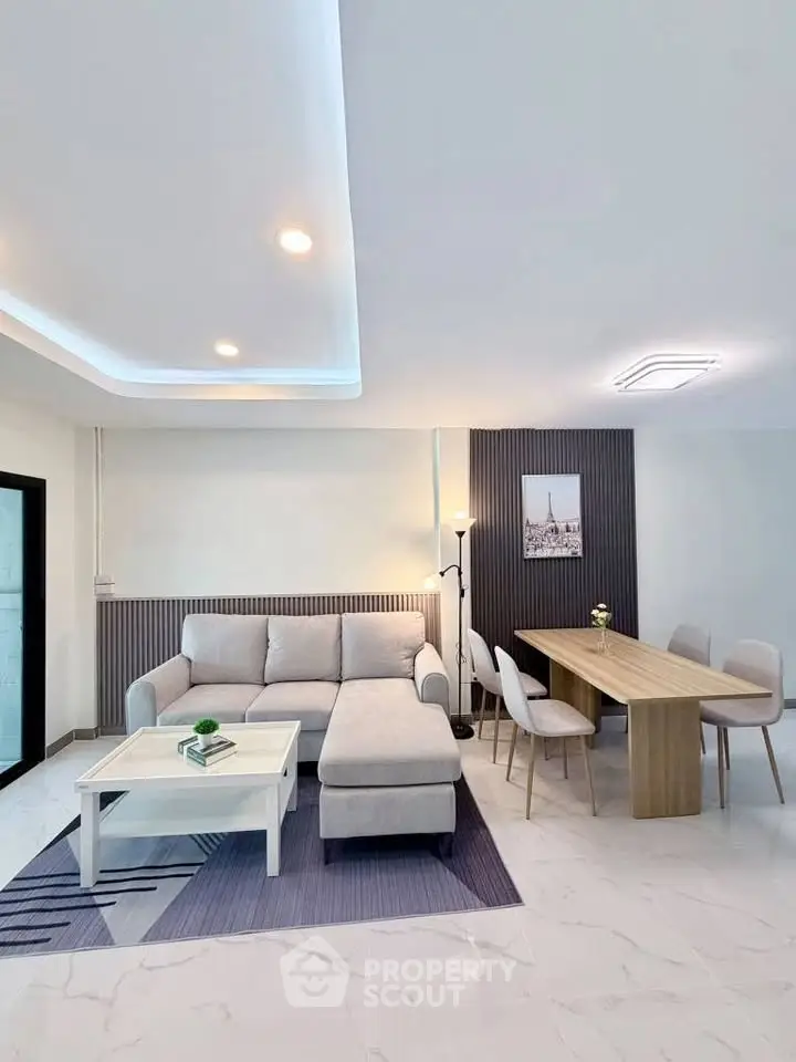 Modern living room with stylish decor and dining area, featuring a cozy sectional sofa and elegant lighting.