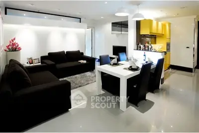 Modern open-plan living room with sleek kitchen and dining area, featuring contemporary furniture and stylish decor.