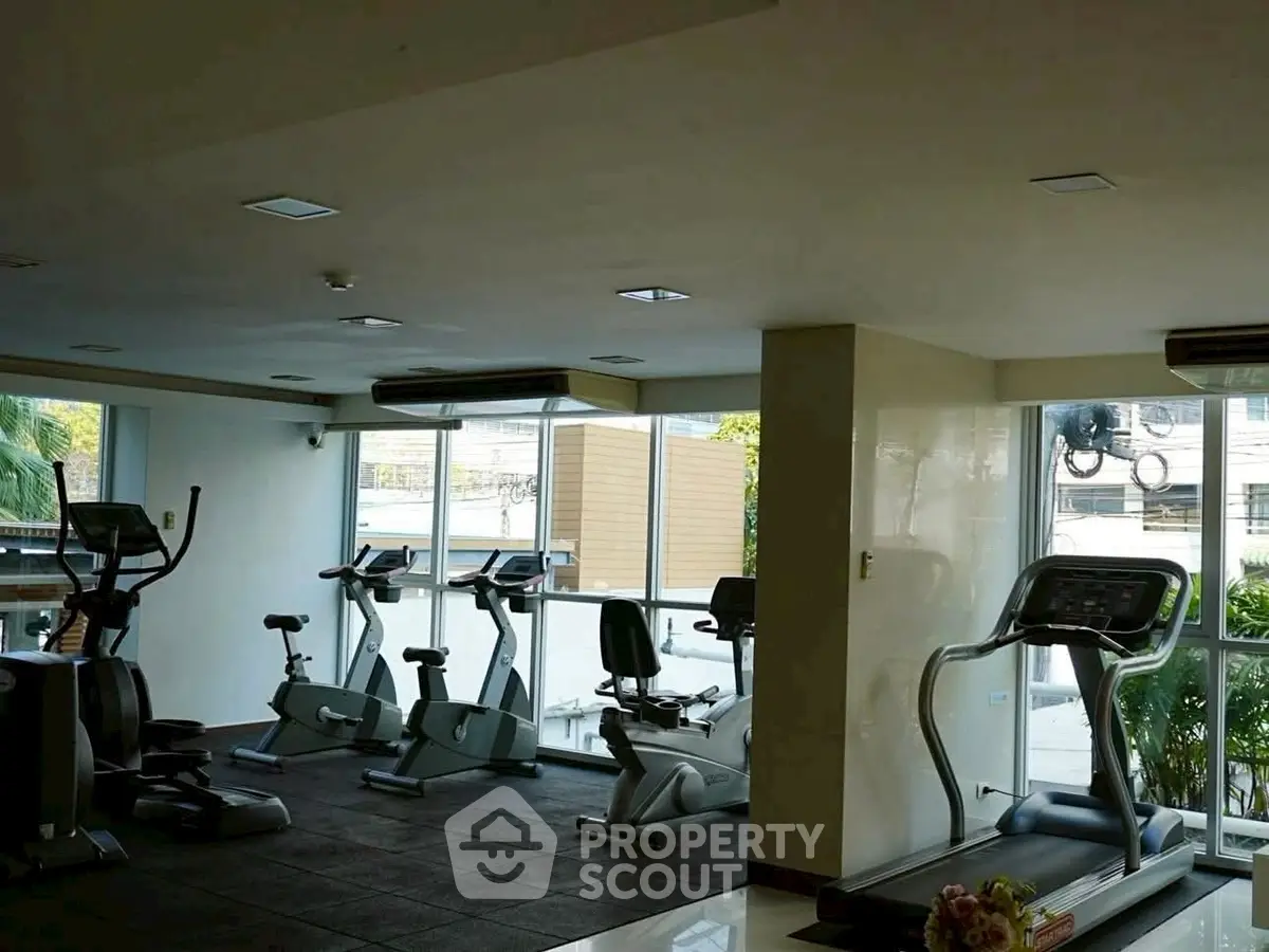 Spacious gym with modern exercise equipment and large windows for natural light.