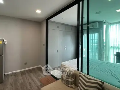 Modern apartment interior with glass partition, cozy living area, and natural light.