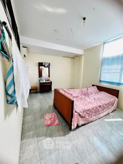 Cozy bedroom with natural light, featuring a wooden bed and vanity, perfect for a serene retreat.