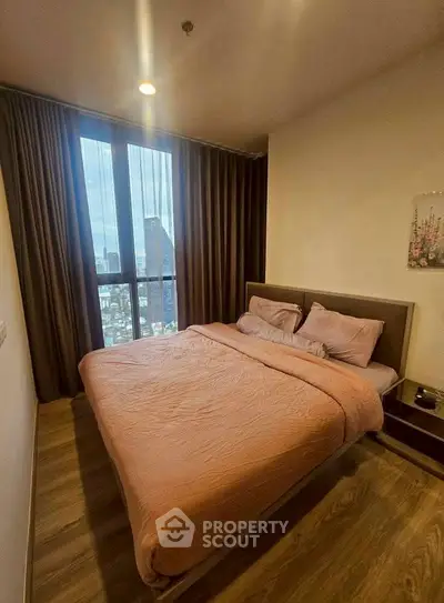 Cozy bedroom with city view, featuring a comfortable bed and warm lighting.
