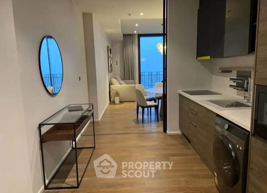 Modern apartment interior with open kitchen and living area, featuring sleek design and balcony view.