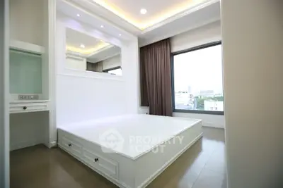 Modern bedroom with large window and built-in storage in a stylish apartment.