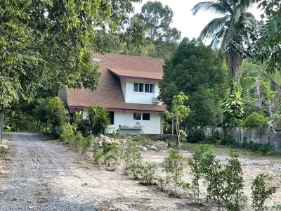 Charming two-story house surrounded by lush greenery and a spacious garden, perfect for nature lovers.