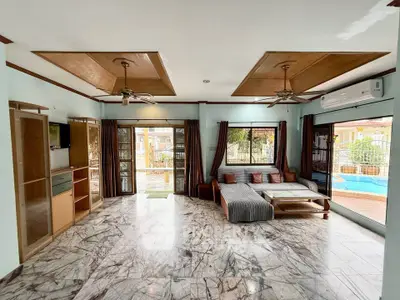 Spacious living room with marble flooring and pool view, featuring modern furniture and ceiling fans.