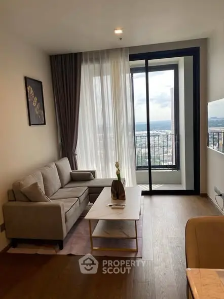 Modern living room with large window and city view, featuring cozy sofa and stylish decor.