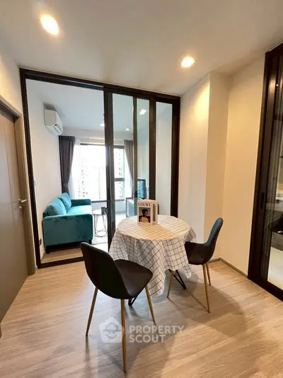 Modern dining area with glass partition leading to cozy living room and city view.