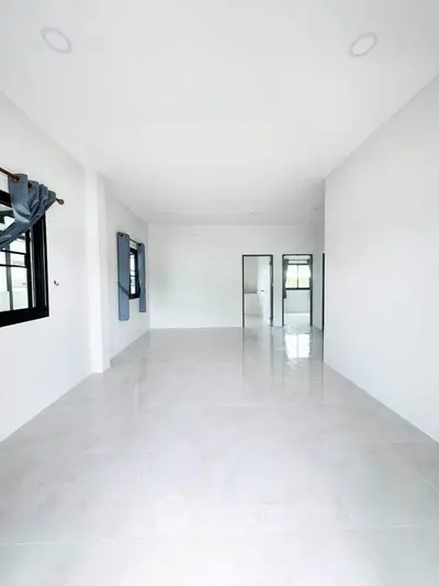 Spacious open-plan living area with large windows and glossy tiled floors, perfect for modern living.