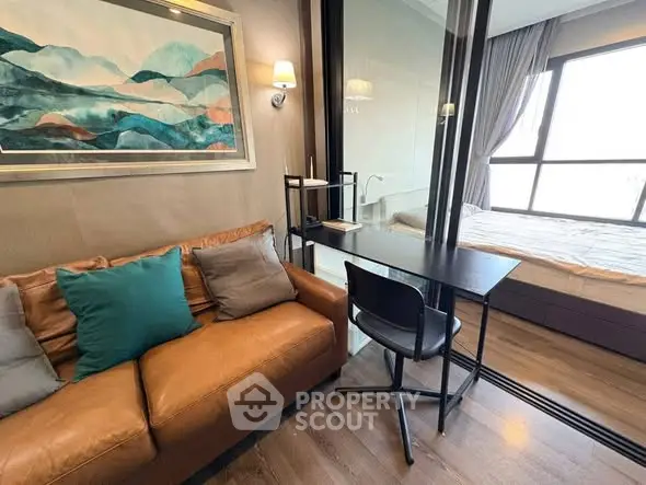 Modern apartment interior with cozy living room and stylish bedroom separated by glass wall.