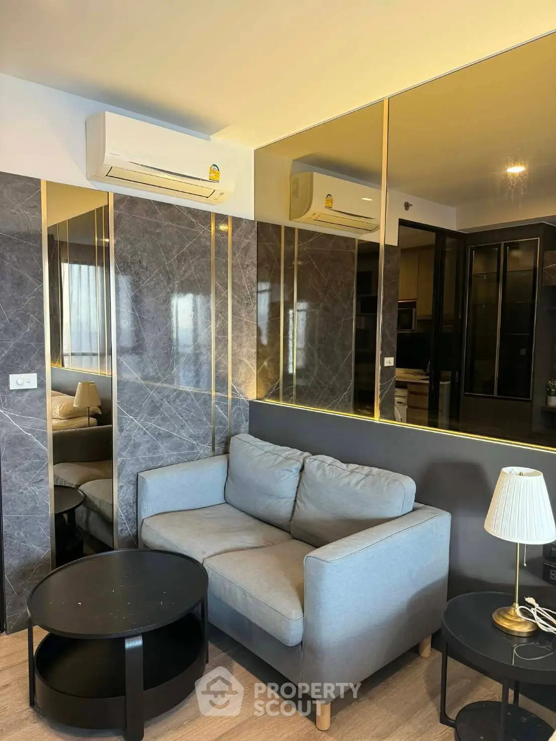 Modern living room with stylish sofa, mirrored walls, and air conditioning unit.