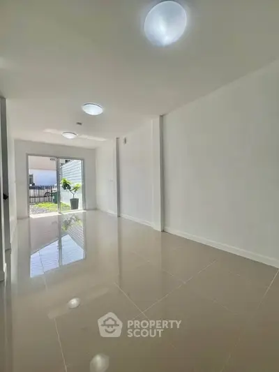 Spacious modern living room with glossy tiled floors and ample natural light.