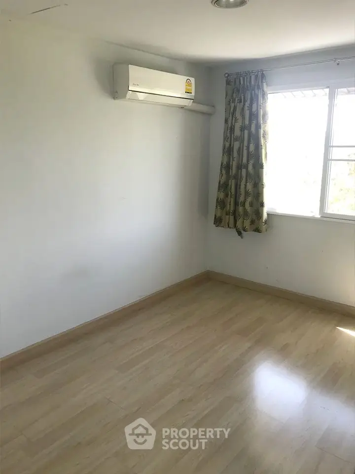Bright empty room with wooden flooring and air conditioning unit, ideal for customization.