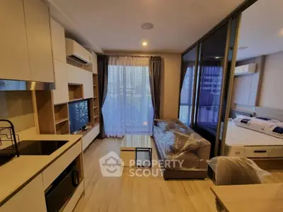 Modern open-plan living room with kitchen and bedroom, featuring sleek design and natural light.