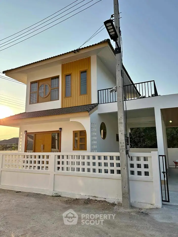 Modern two-story house with unique window design and spacious balcony.