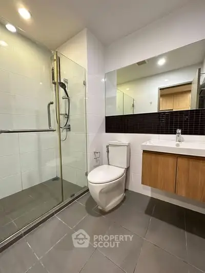 Modern bathroom with glass shower and sleek vanity in contemporary home.