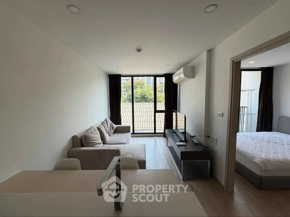 Modern living room with balcony view and adjacent bedroom in a stylish apartment.