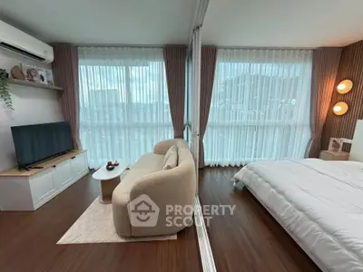 Modern studio apartment with stylish living area and cozy bedroom, featuring large windows and elegant decor.