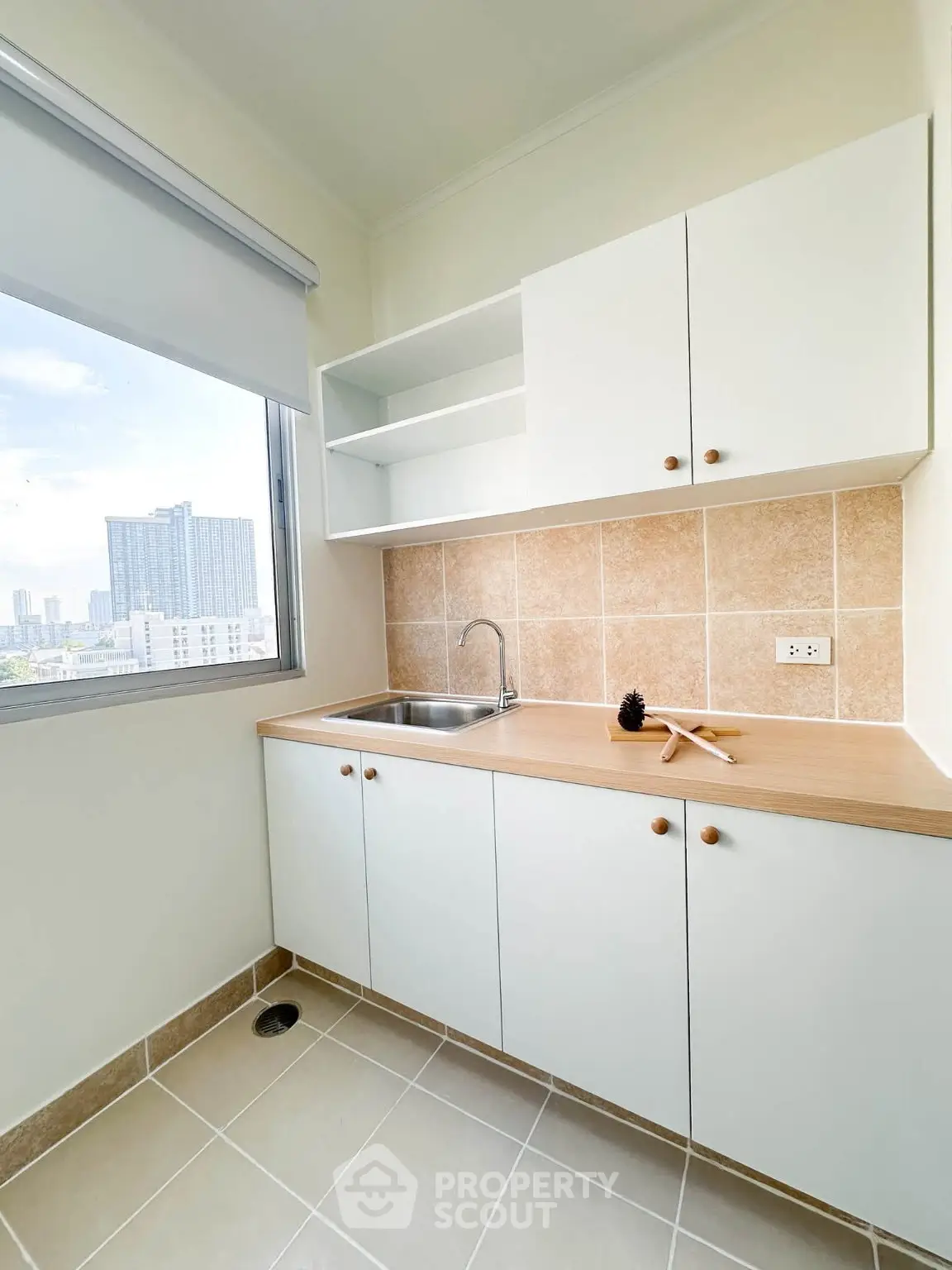 Modern kitchen with open layout and city view, featuring sleek cabinets and tiled backsplash.