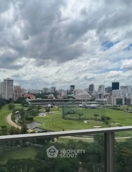 Stunning cityscape view from a high-rise balcony overlooking lush green golf course.