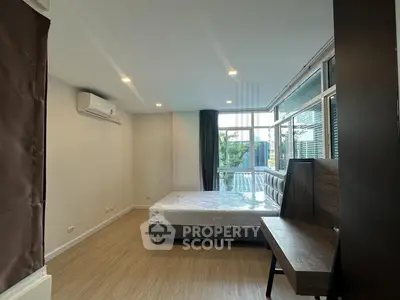 Spacious bedroom with large windows and modern furnishings in a stylish apartment.
