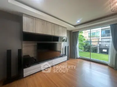 Spacious living room with modern entertainment center and large sliding glass doors to balcony.