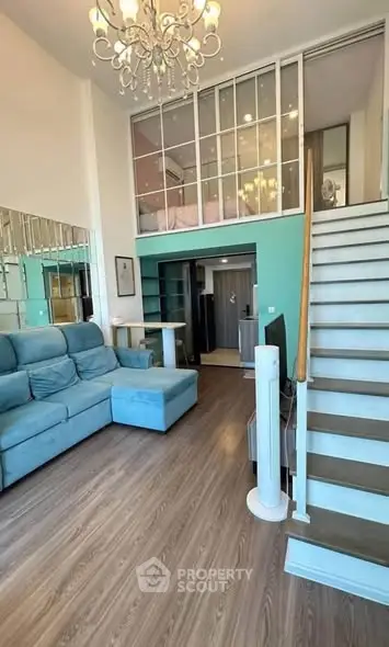 Modern loft-style living room with high ceiling and elegant chandelier