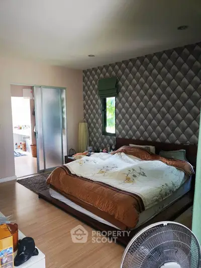 Spacious bedroom with modern decor and natural light, featuring a cozy bed and stylish wallpaper.